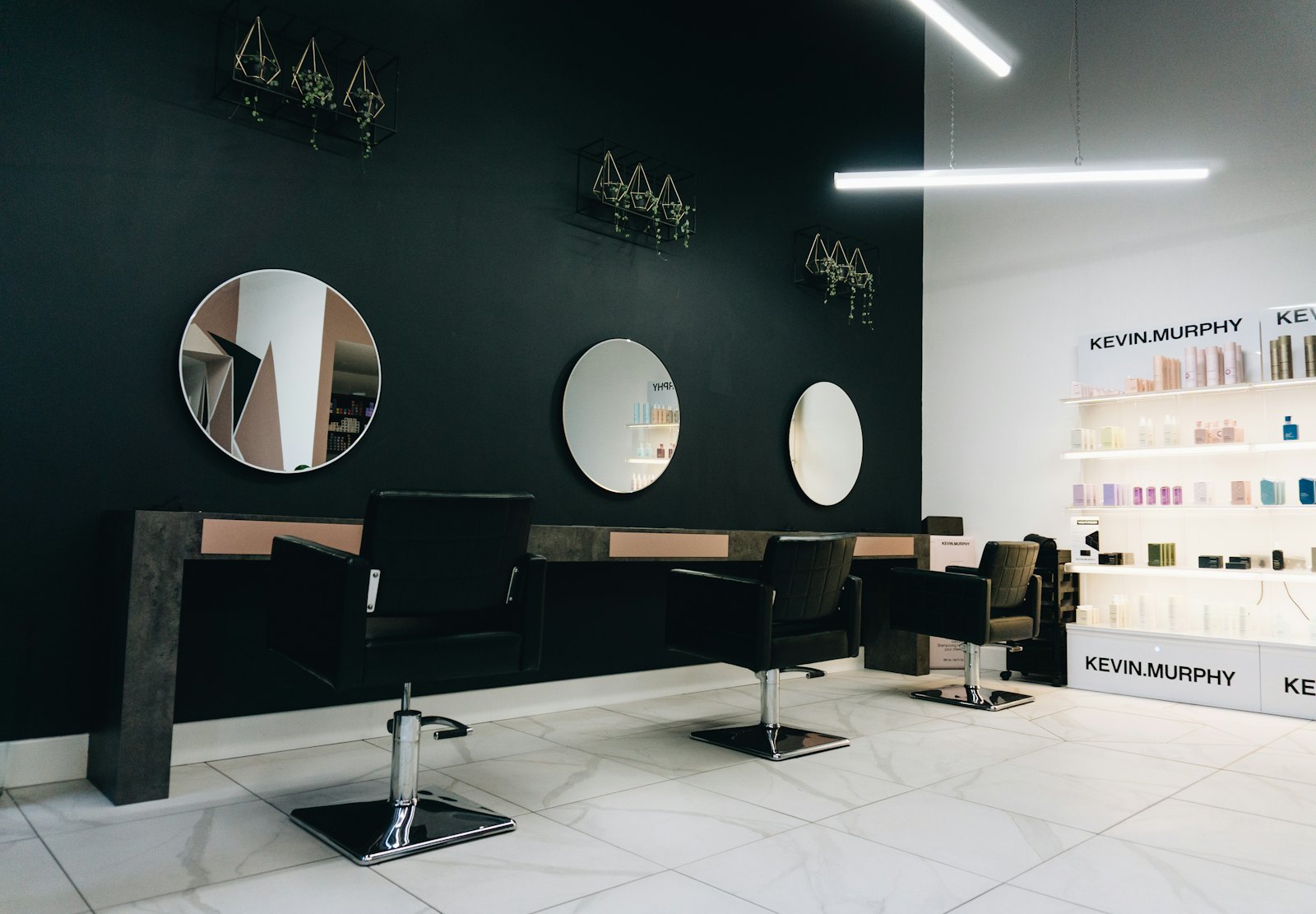 Wnętrze salonu z czarnymi fotelami i okrągłymi lustrami